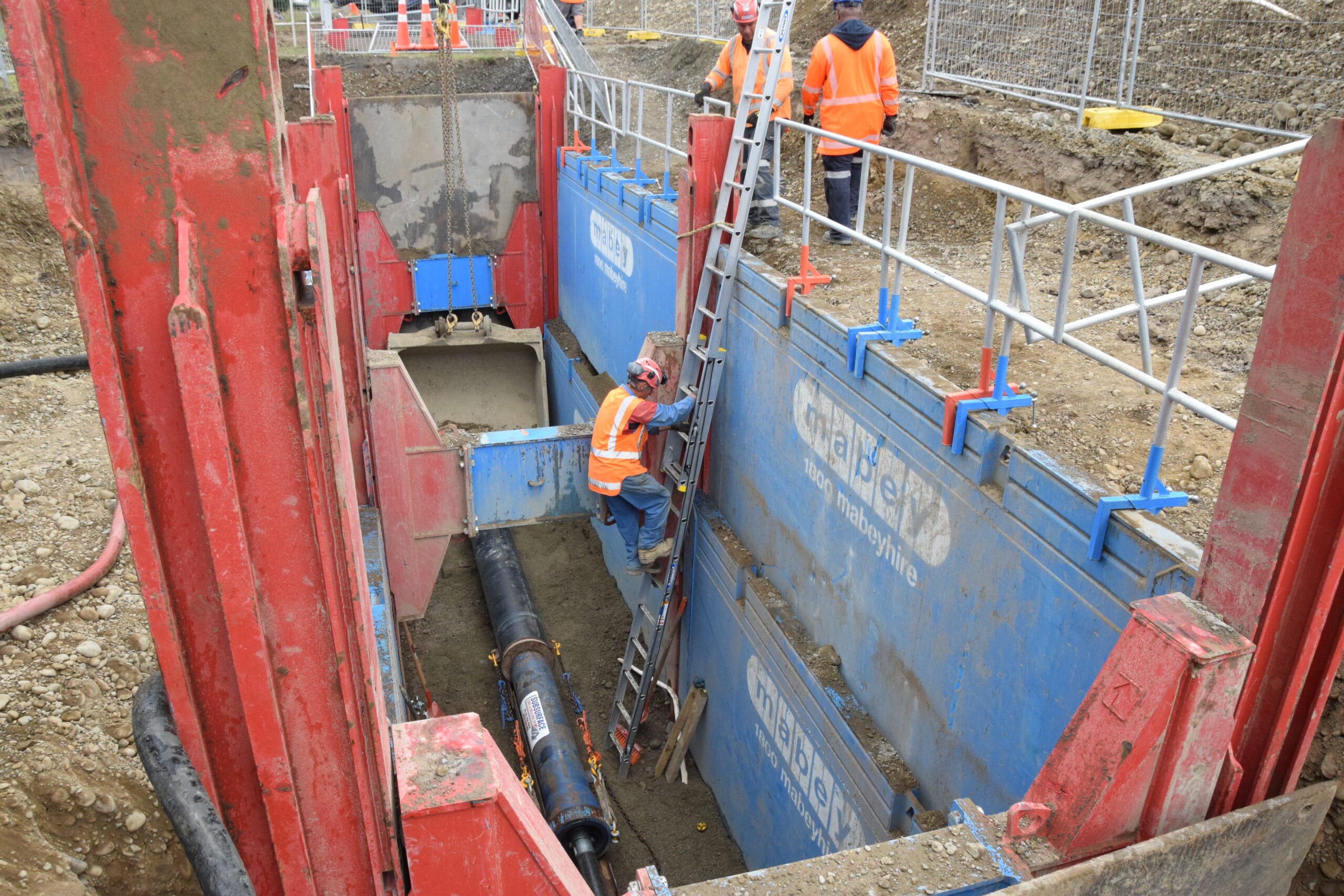 Worker entering trench protected by Mabey trench shoring shield during pipe works