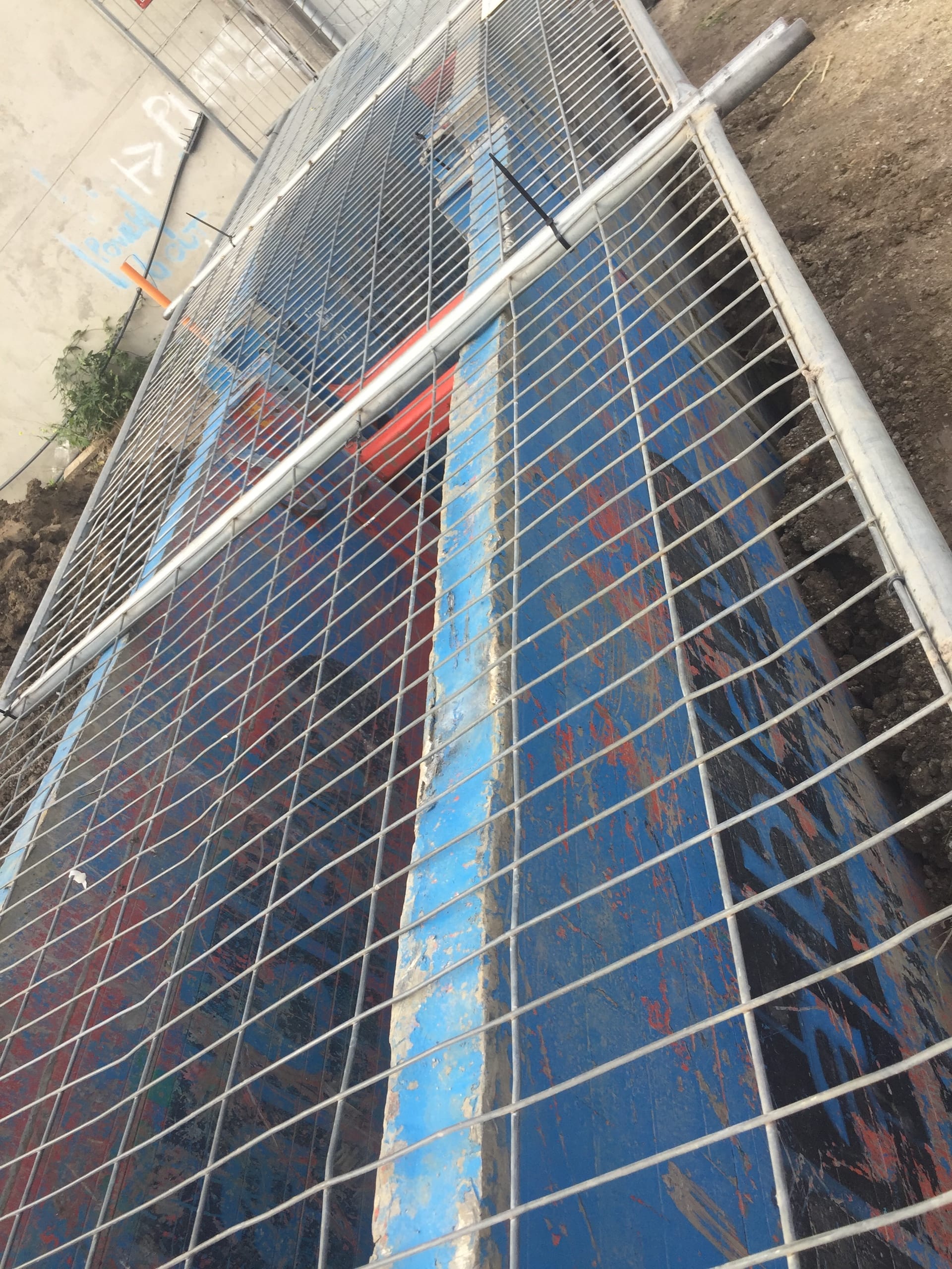 Trench shield panels with safety mesh fencing secured on top at a construction excavation site