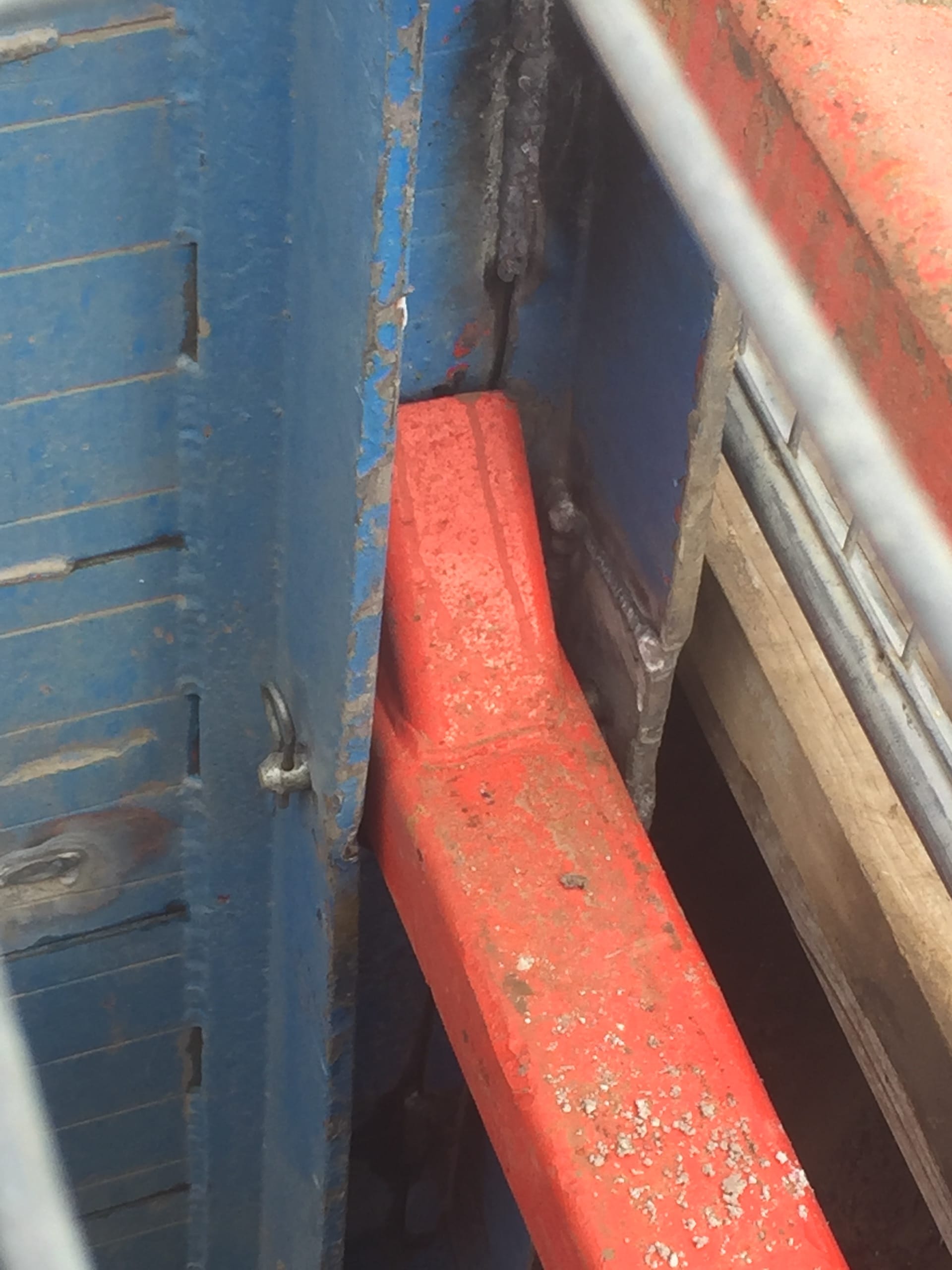 Close-up of a trench box strut connection showing red cross brace secured to blue trench shield wall.