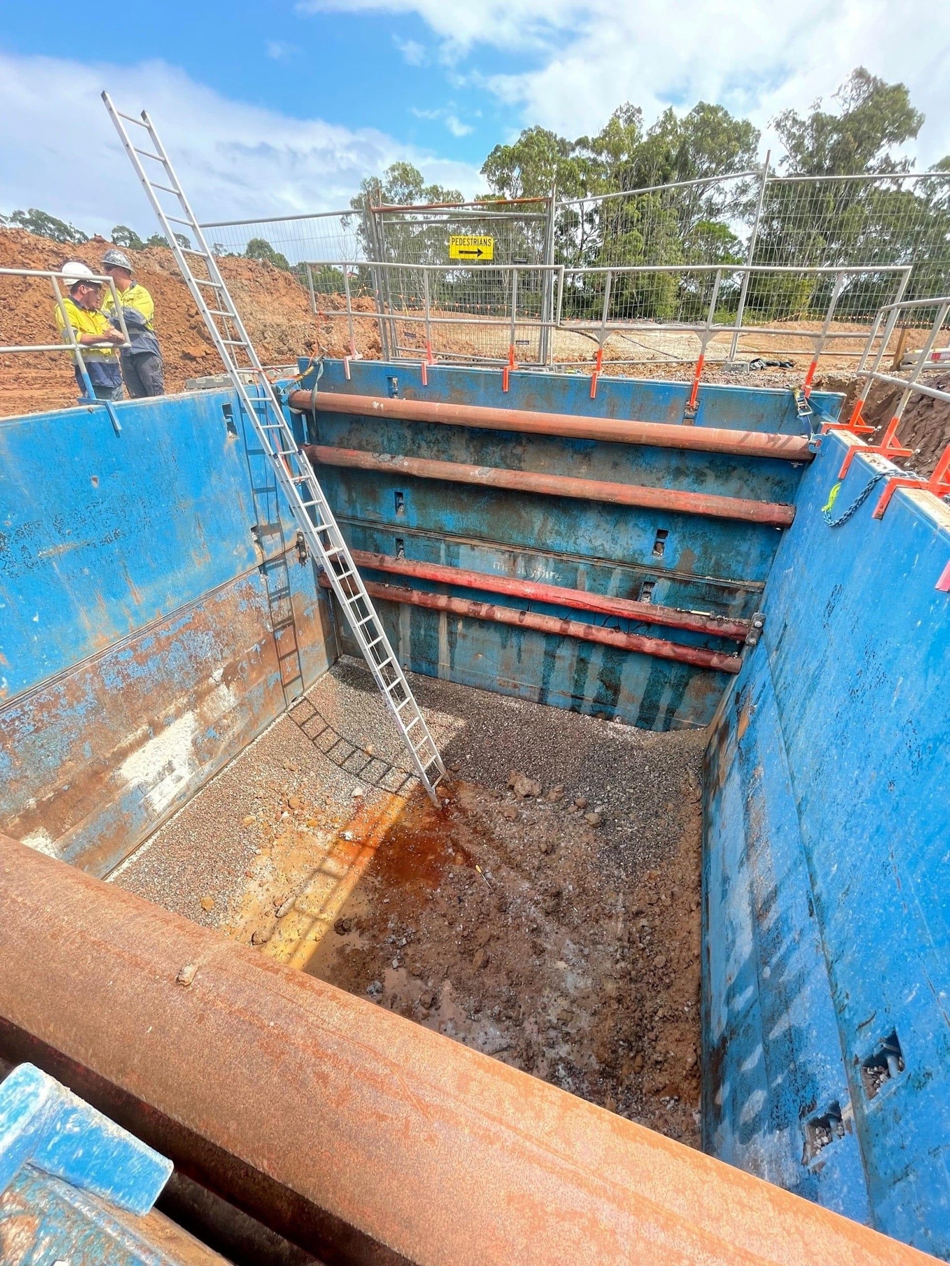 Workers positioning steel trench shields with high-clear configuration for safe excavation