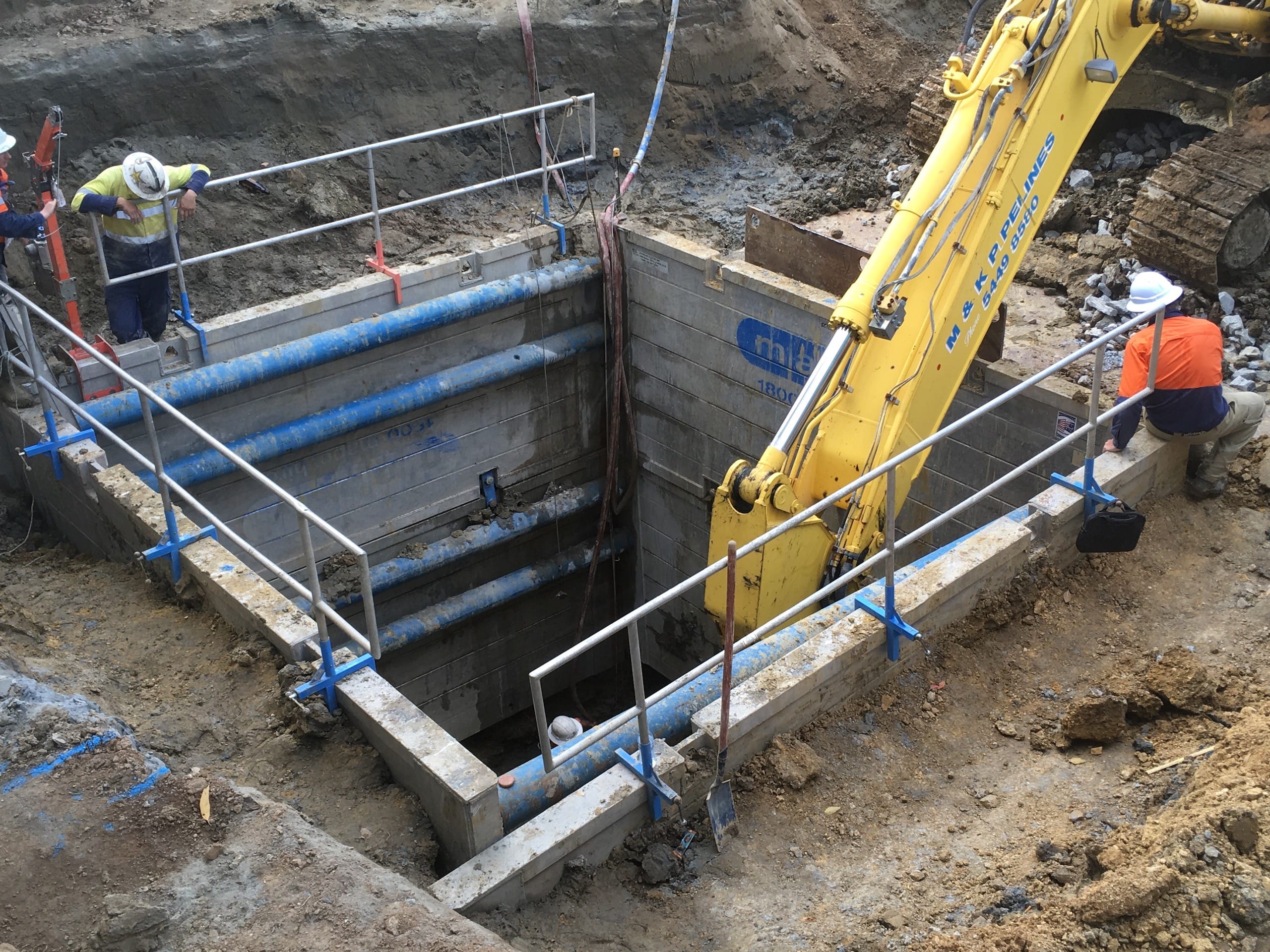 Aluminium trench drag box in excavation with excavator and workers ensuring trench stability and safety